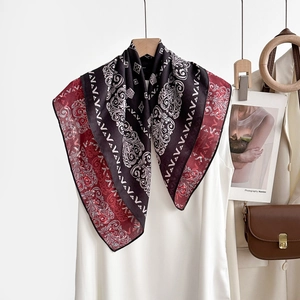 Détail d'un foulard en soie à motif baroque rouge et noir suspendu sur un cintre