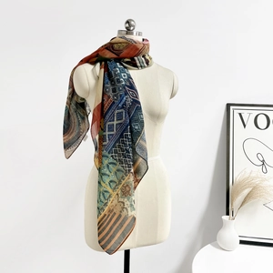 Dettaglio di una sciarpa in seta boho con motivi geometrici drappeggiata su manichino