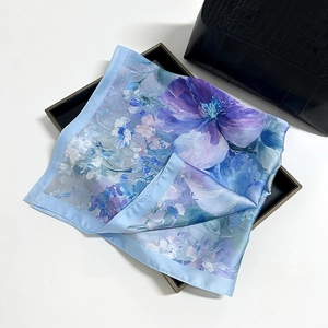 Elegant blue and purple floral silk scarf displayed on a black textured tray