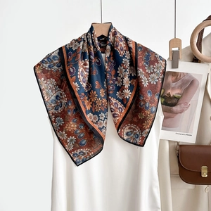 Détail d'un foulard floral vintage à chevrons drapé sur un cintre en bois naturel
