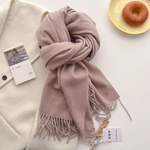 Détail du tissu de l'écharpe pashmina rose poudré doux et texture de franges sur fond beige