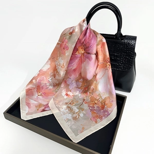 Silk scarf with pink floral print tied elegantly on black faux leather handbag handle