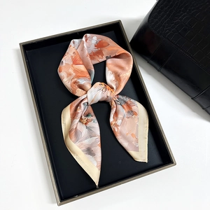 Elegant floral silk scarf in orange and beige tones tied in a decorative bow