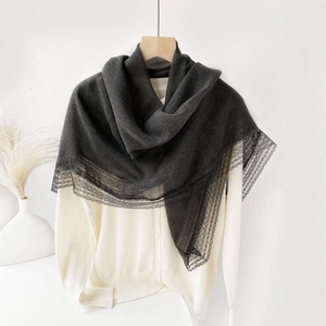 Detail of dark grey scarf with delicate wide lace edge draped on a wooden hanger