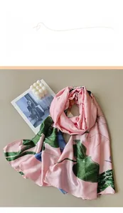Detail of a pink silk scarf with green lotus leaf prints and elegant glossy texture