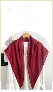 Detail of burgundy triangular silk scarf with black striped edges on wooden hanger