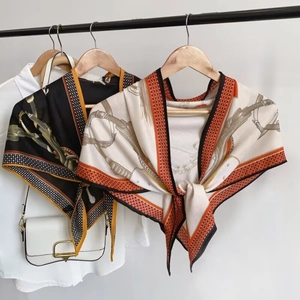 Detail of silk scarf with equestrian horse bit and belt print knotted over a white shirt