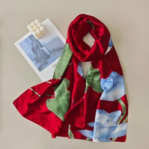 Close-up of red satin scarf with green lotus leaf patterns and soft silk texture