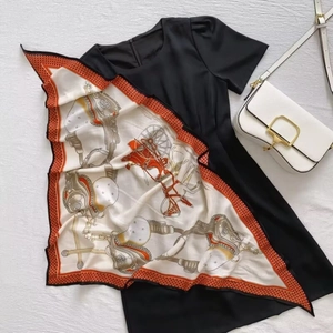 Flat lay of an elegant black dress with a carriage print silk scarf and a white leather bag