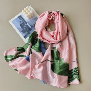 Detail of pink silk scarf featuring green monstera leaves and floral patterns