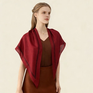 Detailed texture of elegant dark red silk scarf with fine black borders on model shoulders