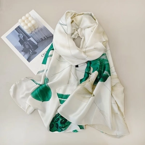 Detailed texture of silk scarf featuring green lotus leaf pattern on white background