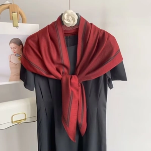 Detail of burgundy knitted shawl with black striped edges on elegant black dress
