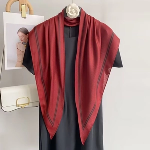Detail of red silk square scarf with black borders styled over a black dress