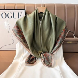 Detail of silk scarf with green paisley patterns draped over a white dress