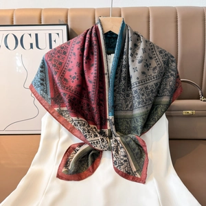 Close-up of elegant paisley silk square scarf with floral borders draped on a white shirt