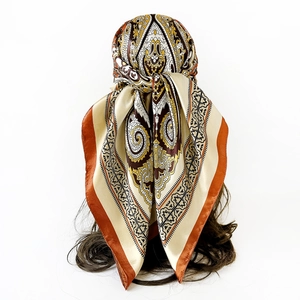 Detailed view of paisley satin headscarf styled on a mannequin head in warm earthy tones