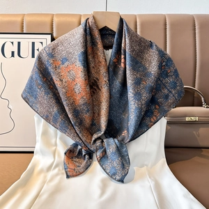 Detail of vintage paisley silk scarf with fringe, hanging next to a classic leather bag