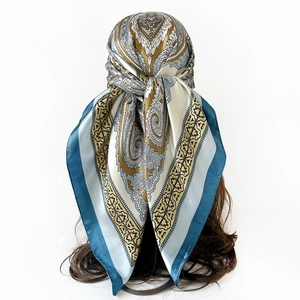 Detail of silk satin paisley square scarf in peacock blue and gold tied as a headscarf