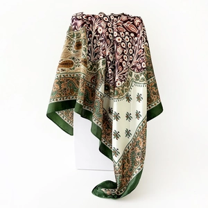 Macro detail of dark green border and vintage paisley patterns on silk satin scarf