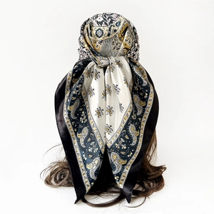 Detailed view of paisley and bee pattern on a satin silk scarf tied on a model head