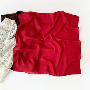 Detailed close-up of premium red silk square scarf showing luxury texture and drape