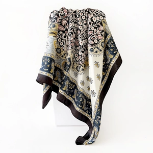 Macro detail of satin silk scarf featuring classic golden paisley patterns and black borders
