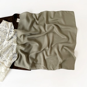 Detail of olive green square scarf with premium herringbone texture and fine rolled edges