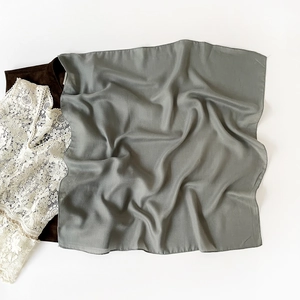 Detail shot of smoky gray silk square scarf paired with white lace and dark brown base