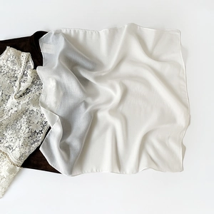 Close-up of white semi-transparent silk scarf with delicate texture and lace accents
