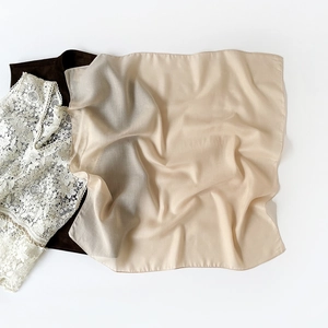 Detail showing the sheer champagne silk texture and herringbone pattern of the square hijab