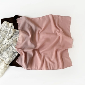 Close-up of a light pink square scarf with semi-transparent texture on a white background