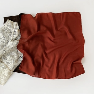 Detail of rust red silk scarf with herringbone texture and glossy satin finish