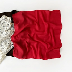 Detailed close-up of vibrant red silk scarf texture with elegant herringbone weave pattern