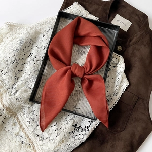 Detail of rust orange linen scarf showing fine herringbone texture and knot styling