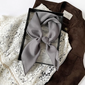 Detail of grey herringbone pattern scarf with elegant satin finish on a glass tray