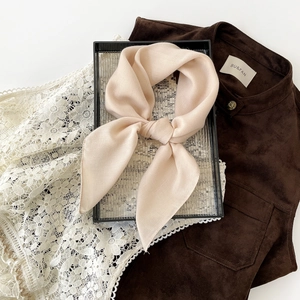 Macro detail of high-quality light peach twill silk scarf showing draping and soft texture