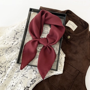 Close-up of wine red silk scarf featuring herringbone weave pattern on tray