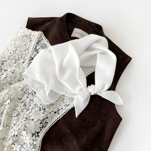 Detail of elegant white lace texture layered with dark brown suede fabric and scarf