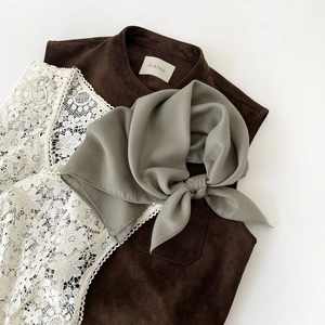 Detail of silk-texture olive scarf layered on a brown suede vest with lace trim