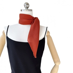 Elegant solid orange silk scarf with herringbone texture tied on a white mannequin neck