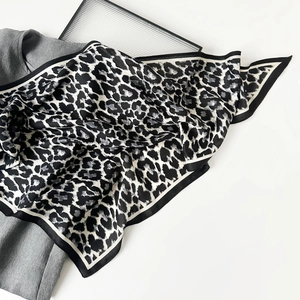 Detail view of large leopard print silk scarf with black and white striped border texture