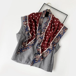 Détail d'un foulard en soie bordeaux avec motif paisley et pois blancs sur un gilet