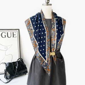 Détail d'un foulard en soie à motif paisley et pois, porté avec ceinture comme paréo chic