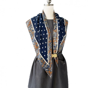 Foulard en soie à pois et motif paisley bleu marine porté sur une robe grise
