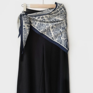 Détail de l'écharpe imprimée carte bleue et blanche avec motifs d'architecture sur pantalon