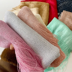 Detail shot of shimmering metallic yarn scarves with long fringe tassels in various colors