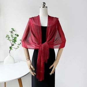 Detail of a red knit shawl with sparkling metallic threads and fringe on a model