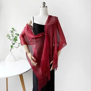 Close-up of red sparkling metallic shawl with long fringe tassels over a black dress