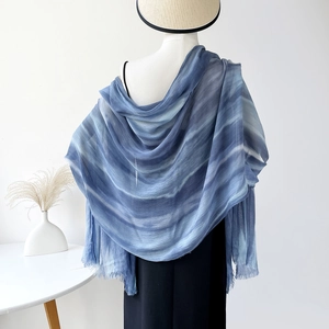 Close-up of lightweight blue gradient scarf with delicate fringe details on a mannequin